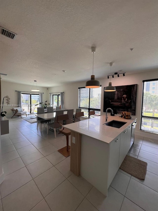 8001 NW 41st St Unit F-207, Doral, FL 33166 - kitchen with a sink, light tile patterned floors, a textured ceiling, hanging light fixtures, and a kitchen island with sink