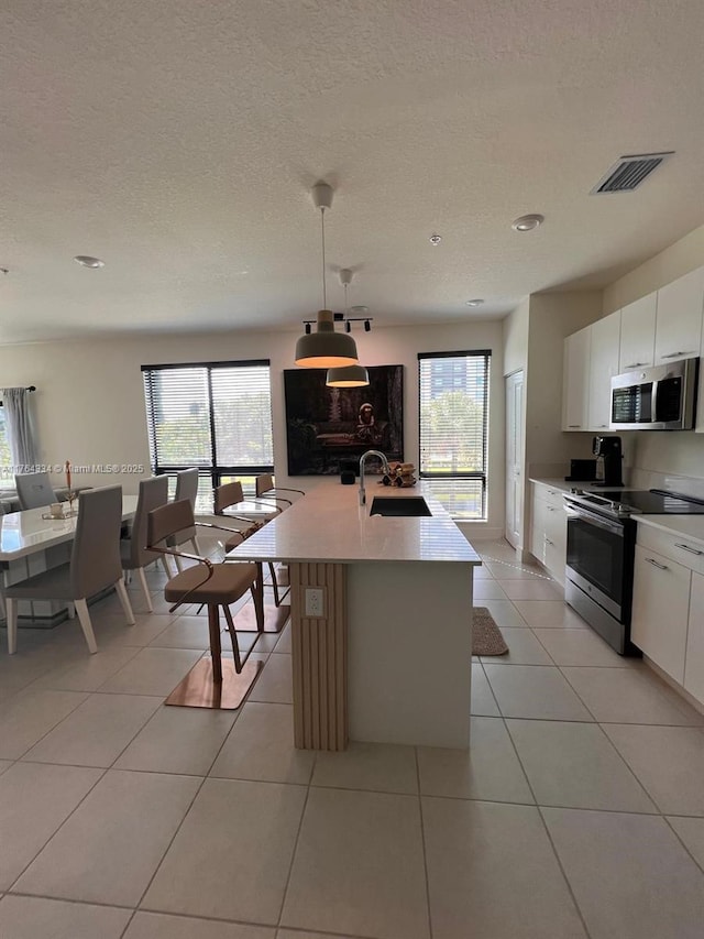 kitchen featuring light tile patterned flooring, stainless steel appliances, a wealth of natural light, and a sink