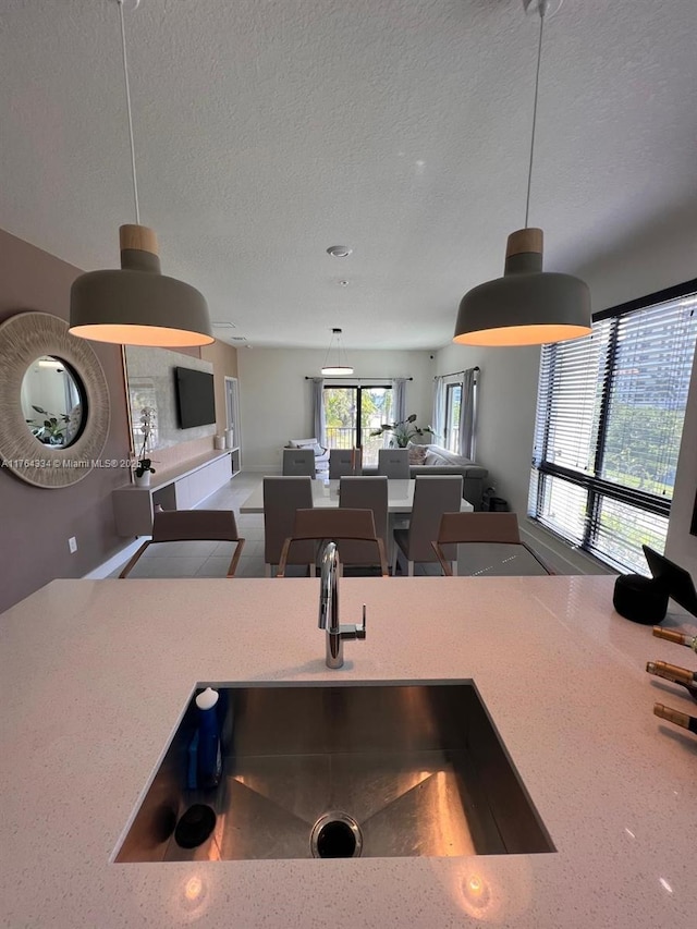 8001 NW 41st St Unit F-207, Doral, FL 33166 - kitchen with a sink, a textured ceiling, hanging light fixtures, open floor plan, and light countertops