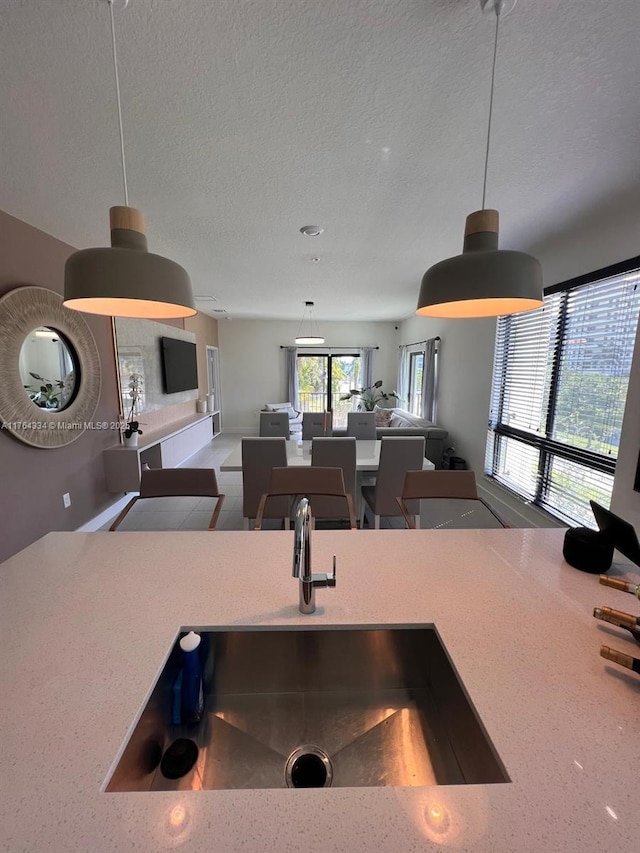 kitchen with a sink, decorative light fixtures, a textured ceiling, open floor plan, and light countertops