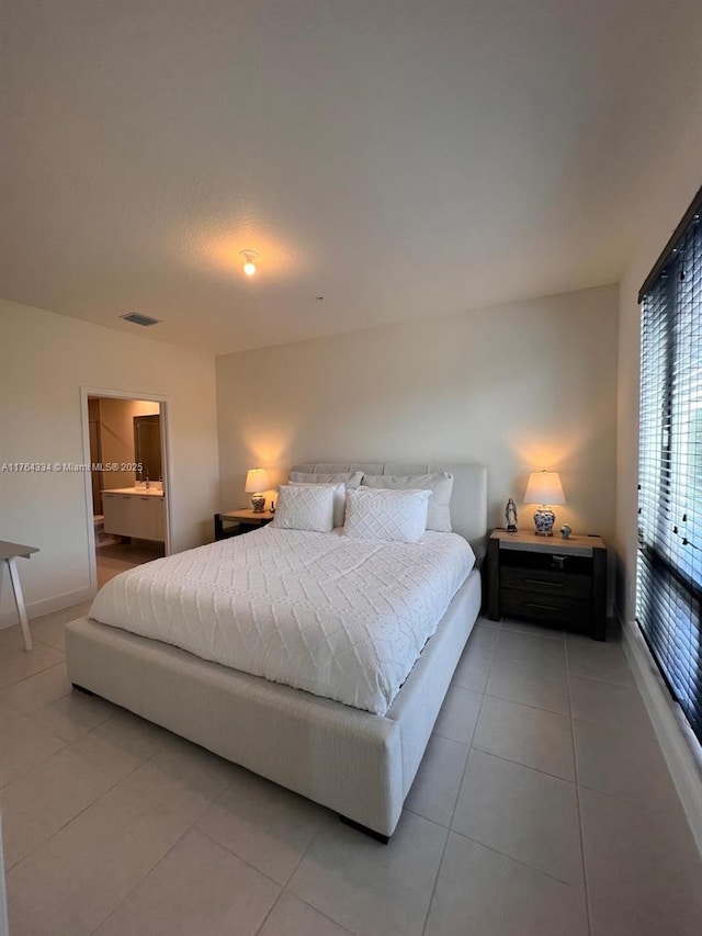 bedroom with visible vents, ensuite bath, and light tile patterned flooring