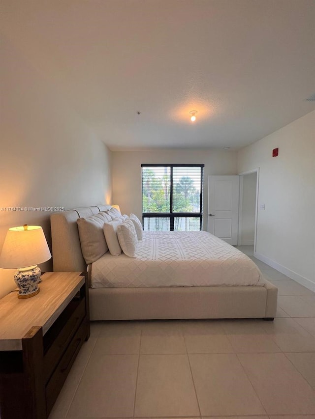 bedroom with light tile patterned flooring and baseboards