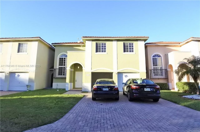 mediterranean / spanish-style home with stucco siding, a front lawn, a garage, a tile roof, and decorative driveway