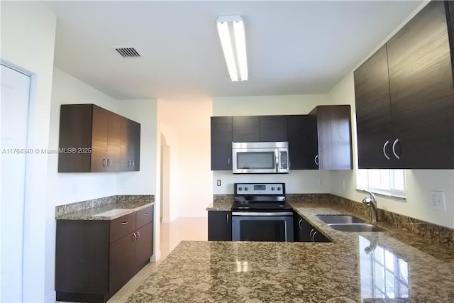 kitchen with visible vents, dark stone counters, appliances with stainless steel finishes, modern cabinets, and a sink