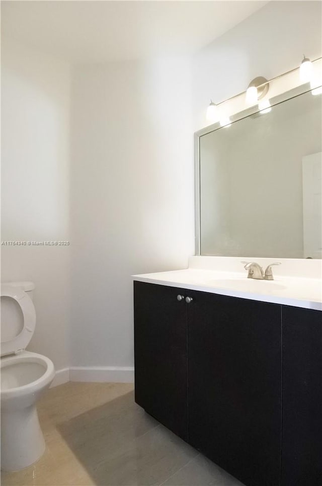 bathroom with vanity, toilet, and baseboards