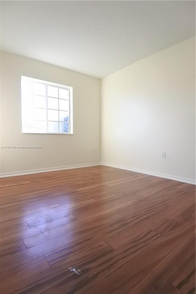 unfurnished room with baseboards and wood finished floors