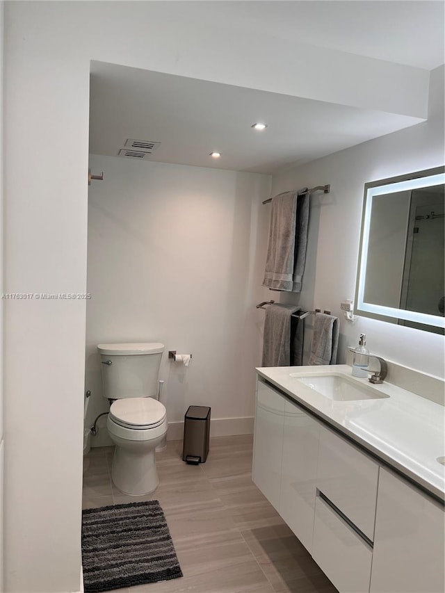 bathroom featuring visible vents, toilet, recessed lighting, baseboards, and vanity