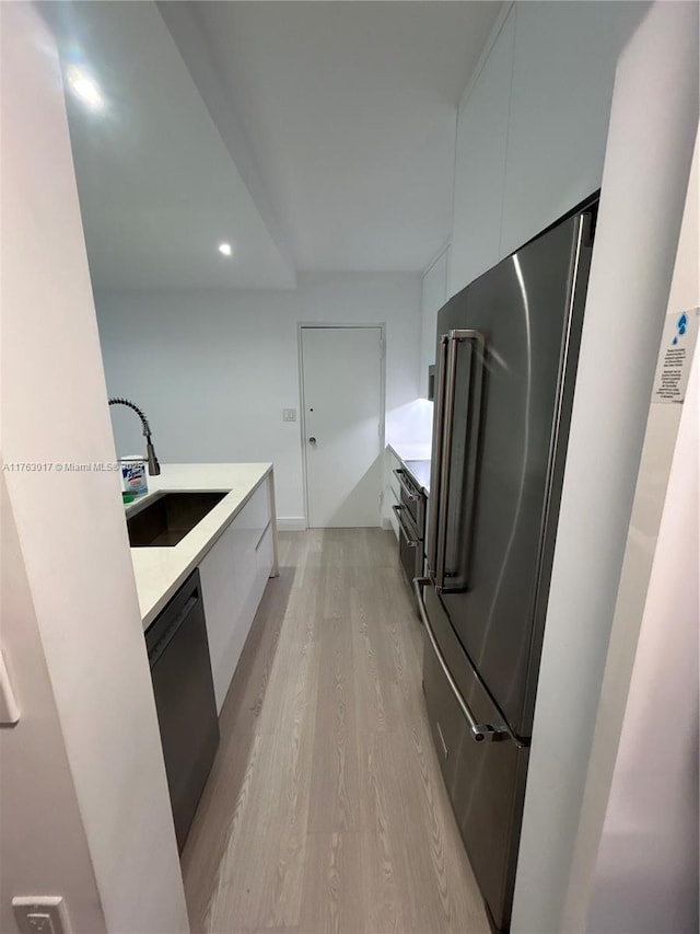 kitchen featuring modern cabinets, a sink, light wood-style floors, dishwashing machine, and high end refrigerator