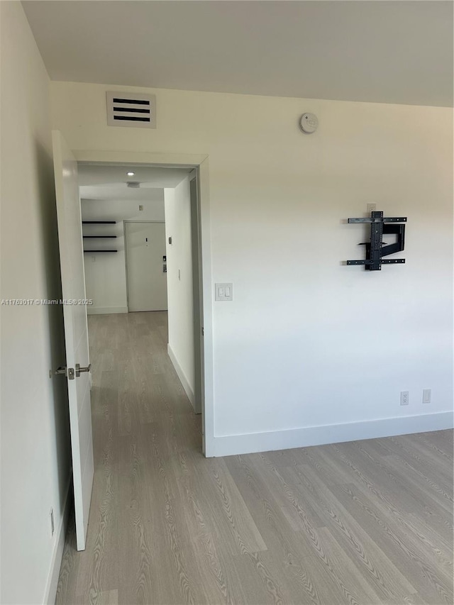 hall with visible vents, baseboards, and light wood-type flooring