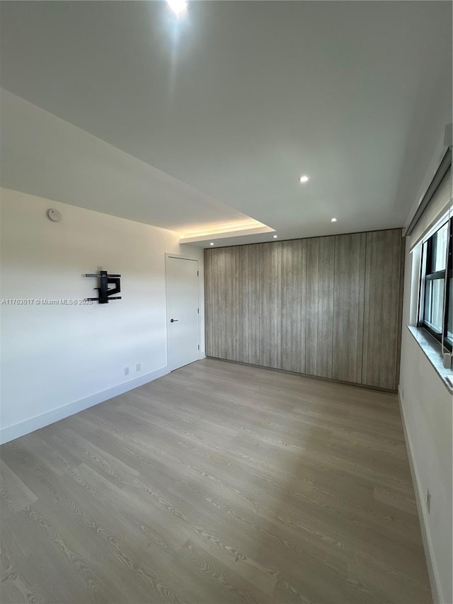 empty room with light wood-type flooring, baseboards, and recessed lighting