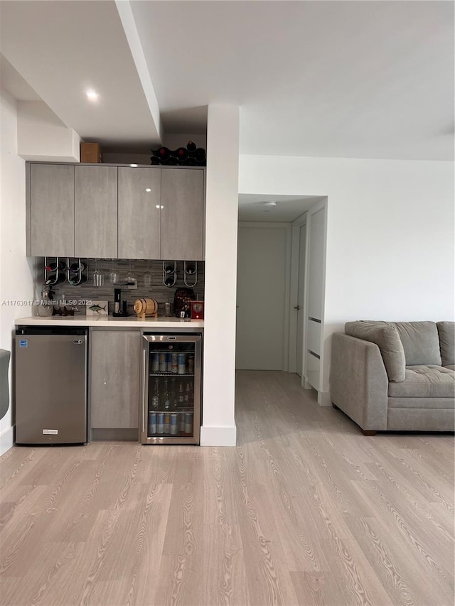 kitchen with modern cabinets, light wood-style flooring, fridge, wine cooler, and light countertops