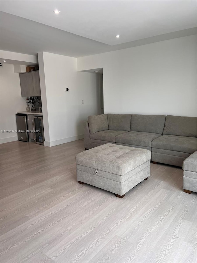 living room featuring recessed lighting, wine cooler, light wood finished floors, baseboards, and indoor bar