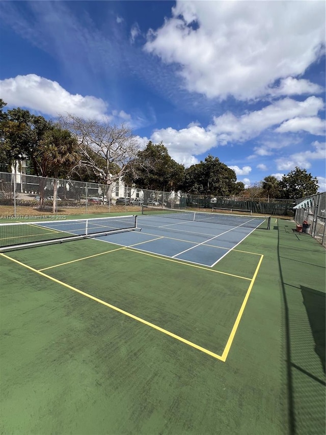 view of tennis court with community basketball court and fence