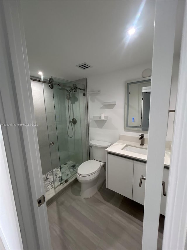 full bathroom with visible vents, toilet, a shower stall, and vanity
