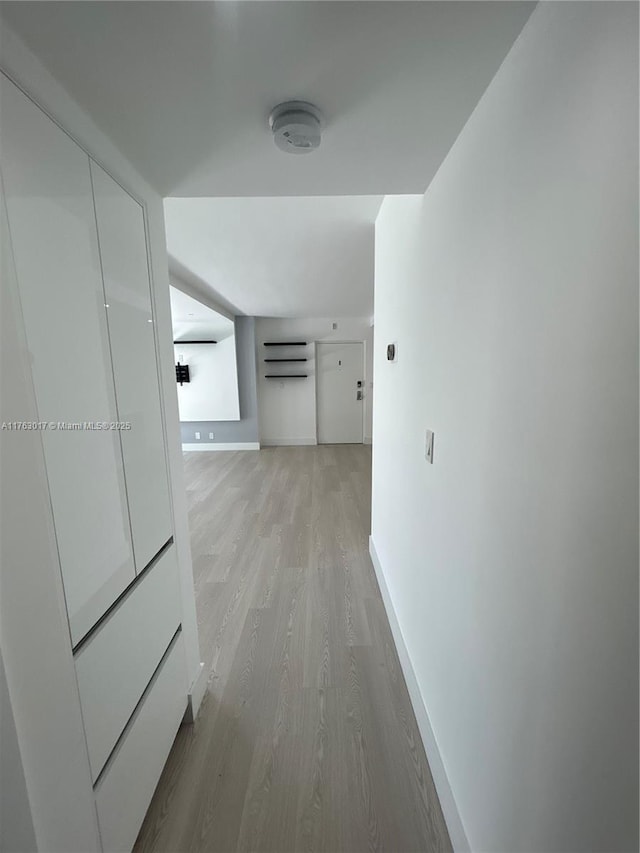 hall featuring light wood-type flooring and baseboards