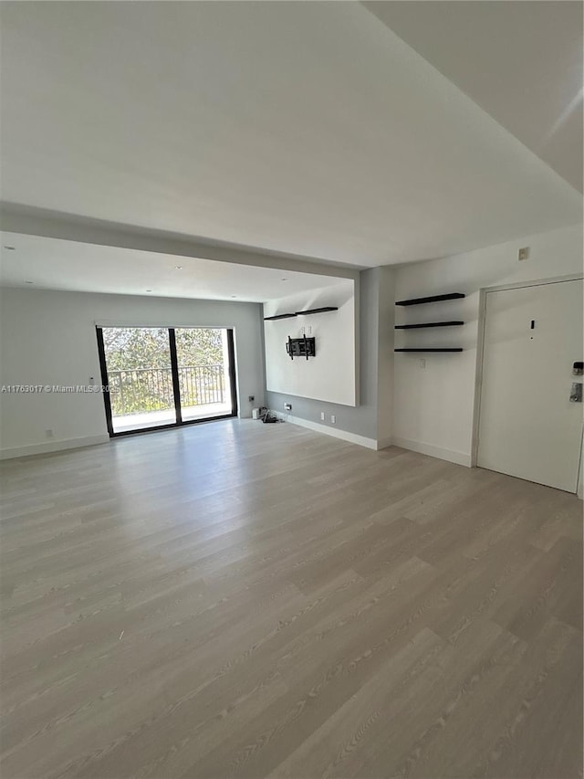 unfurnished living room featuring light wood-style flooring and baseboards