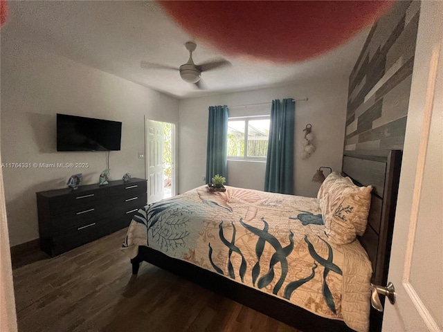 bedroom with a fireplace, dark wood-type flooring, and a ceiling fan