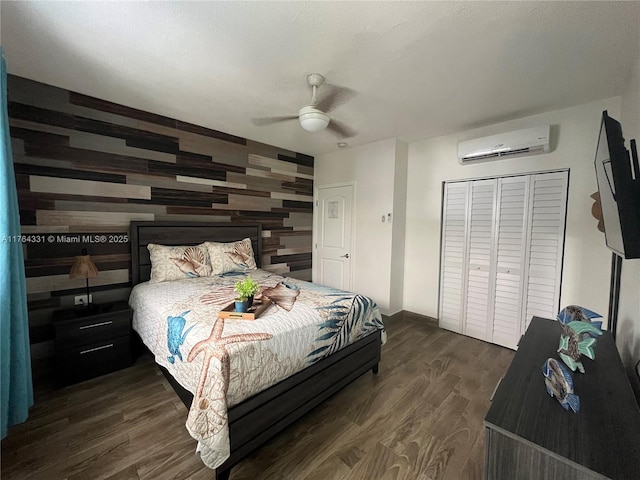 bedroom featuring an accent wall, wood walls, a wall mounted air conditioner, dark wood-style floors, and a ceiling fan