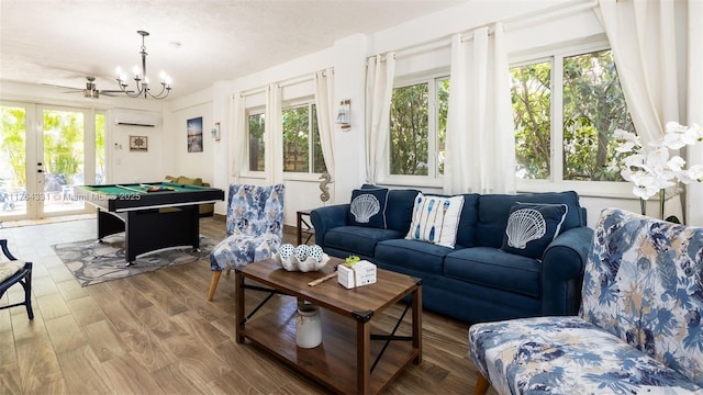 living area featuring french doors, an inviting chandelier, wood finished floors, a wall mounted AC, and billiards