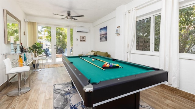 playroom featuring french doors, an AC wall unit, a ceiling fan, and wood finished floors