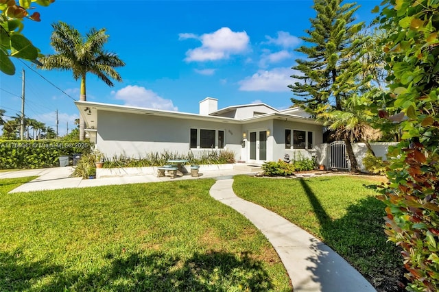 back of property with stucco siding, french doors, a yard, and a gate