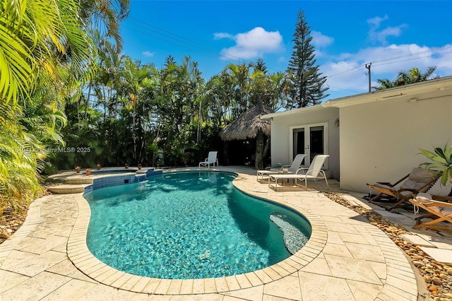 view of swimming pool featuring a patio, french doors, and a pool with connected hot tub