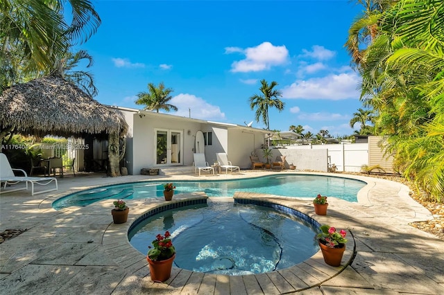 view of pool with french doors, a patio, a pool with connected hot tub, and fence