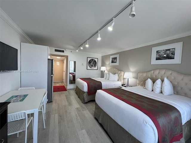 bedroom featuring visible vents, freestanding refrigerator, track lighting, crown molding, and light wood-type flooring