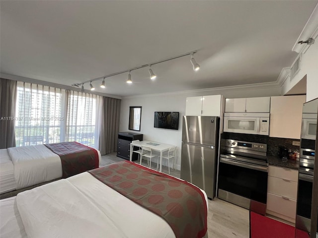 bedroom featuring visible vents, light wood-style floors, crown molding, and freestanding refrigerator