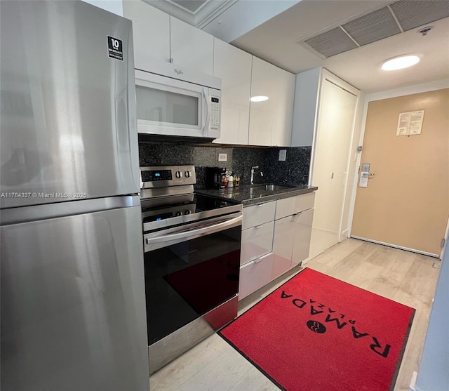 kitchen featuring visible vents, a sink, tasteful backsplash, stainless steel appliances, and white cabinets