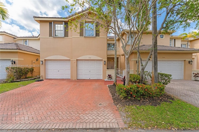 view of front of property with a tile roof, a garage, driveway, and stucco siding