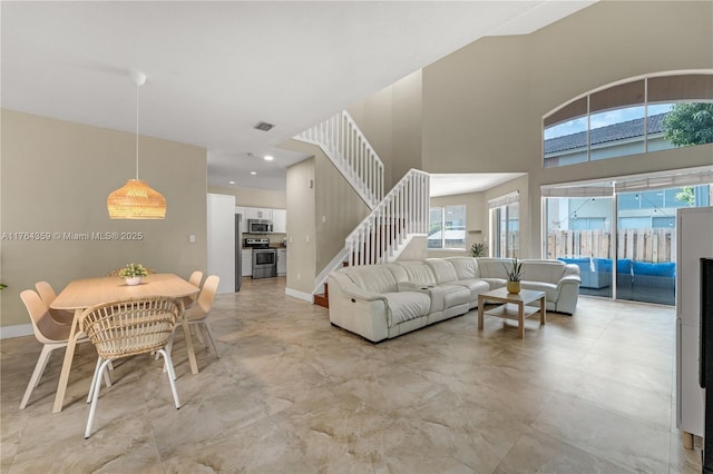 living room featuring stairway, recessed lighting, baseboards, and a towering ceiling