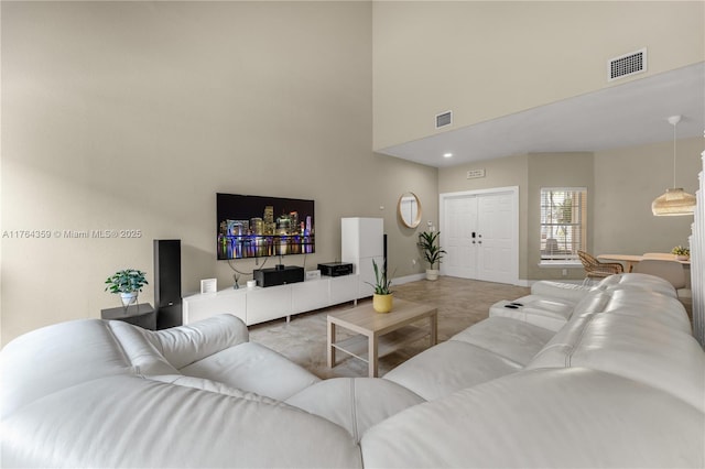 living area with visible vents, baseboards, and a towering ceiling