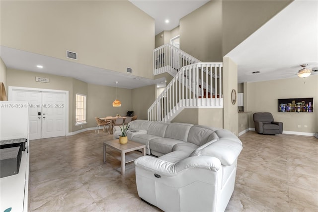 living room featuring a high ceiling, stairway, baseboards, and visible vents