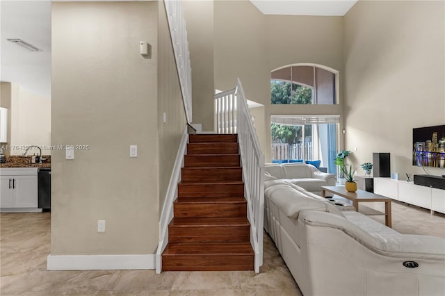 stairs featuring visible vents, baseboards, and a towering ceiling