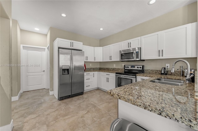 kitchen featuring light stone counters, recessed lighting, appliances with stainless steel finishes, white cabinets, and a sink