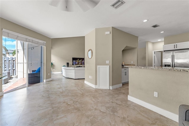 unfurnished living room featuring a ceiling fan, visible vents, and baseboards