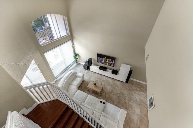 living room with visible vents, baseboards, and a towering ceiling