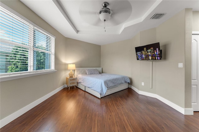 bedroom with a raised ceiling, baseboards, visible vents, and dark wood-style flooring