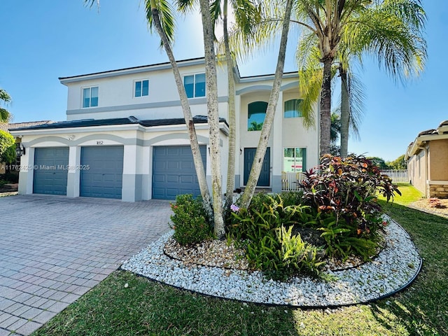 view of front of house with decorative driveway, an attached garage, and stucco siding