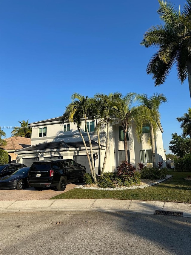 view of front of house featuring stucco siding, decorative driveway, a garage, and fence