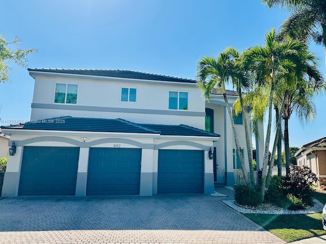 view of front of property with stucco siding, a tiled roof, decorative driveway, and a garage