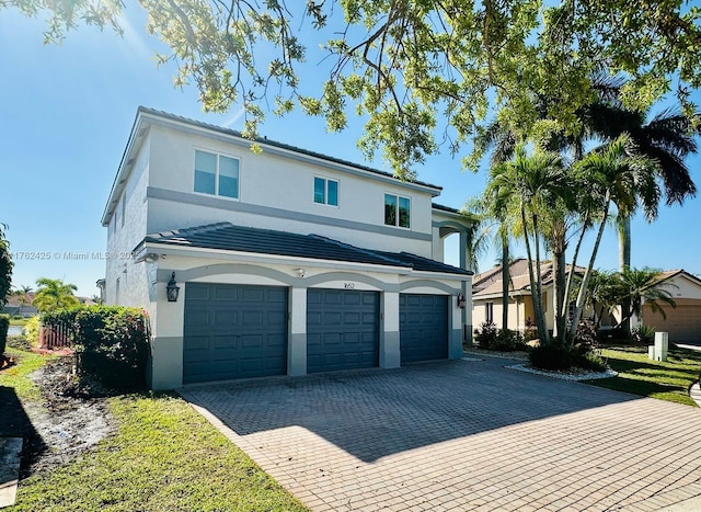 traditional home with stucco siding, decorative driveway, and an attached garage