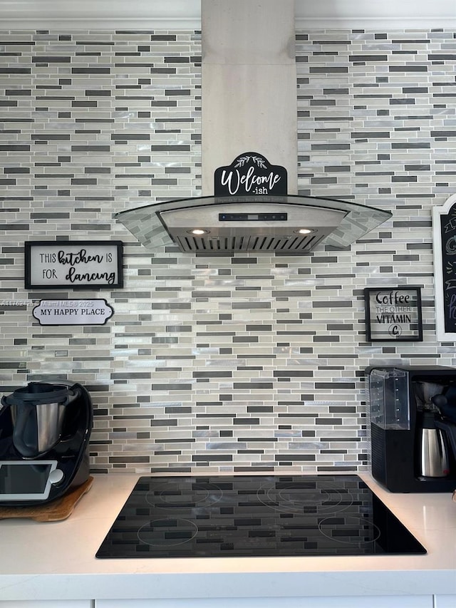 room details featuring black electric stovetop, tasteful backsplash, light countertops, and wall chimney range hood