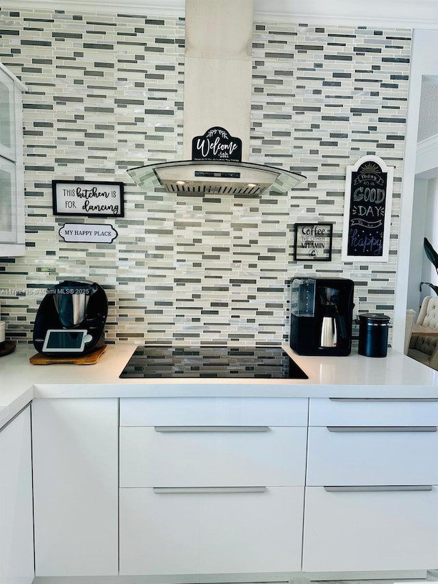 kitchen featuring light countertops, white cabinetry, black electric stovetop, modern cabinets, and tasteful backsplash