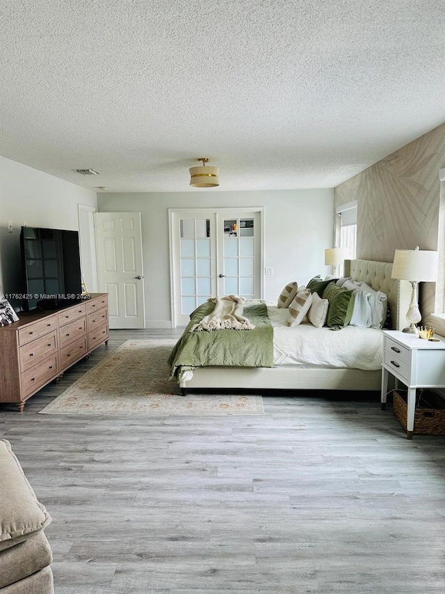 bedroom with wood finished floors, visible vents, and a textured ceiling