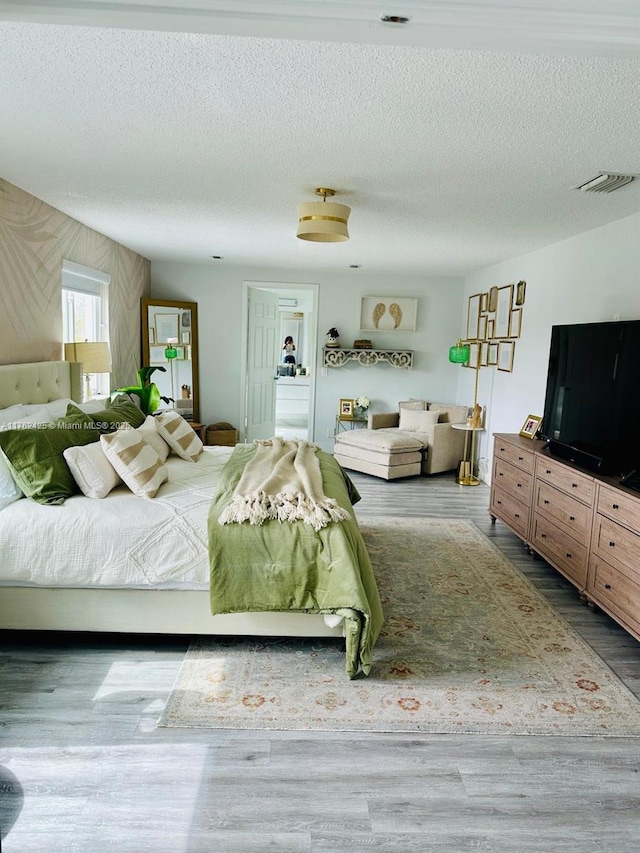 unfurnished bedroom featuring wood finished floors, visible vents, and a textured ceiling