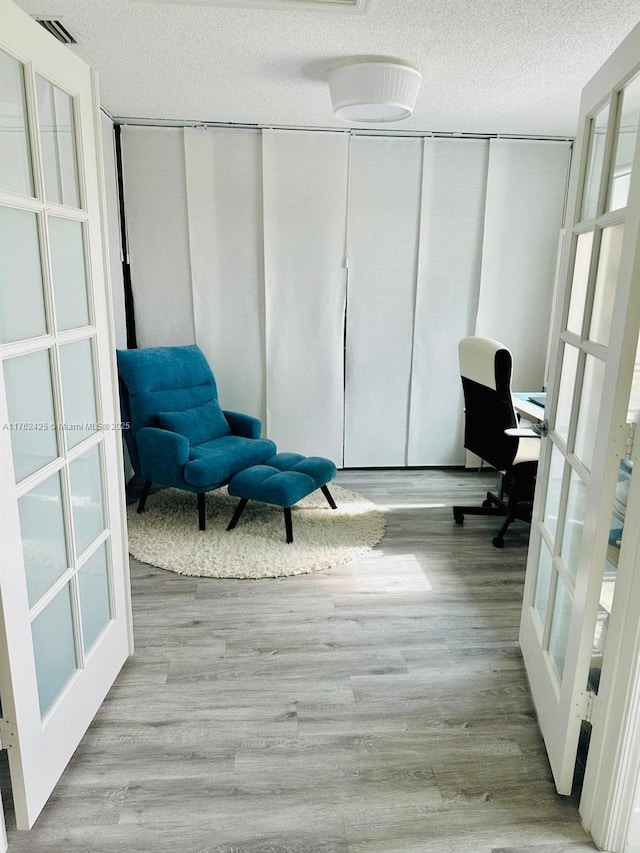 office featuring wood finished floors, french doors, visible vents, and a textured ceiling