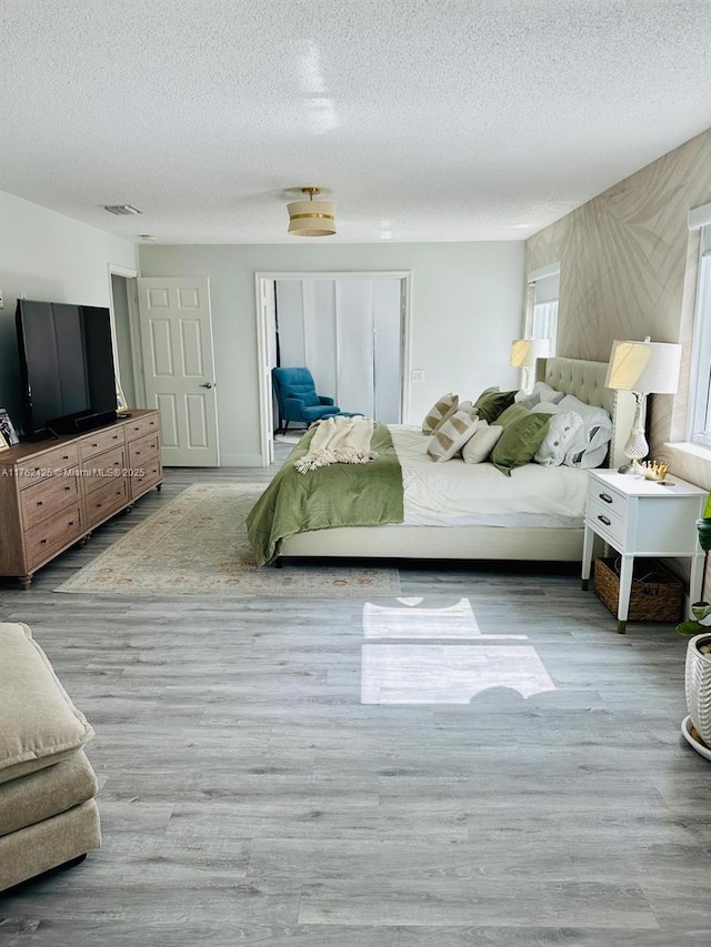 bedroom featuring visible vents, a textured ceiling, and wood finished floors