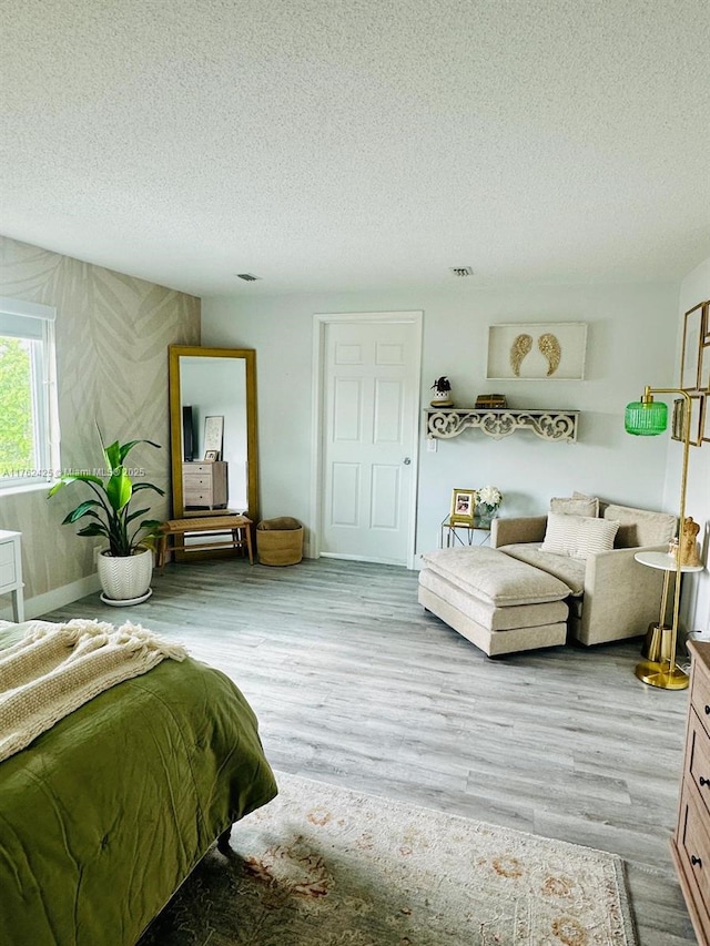 bedroom featuring visible vents, a textured ceiling, and wood finished floors